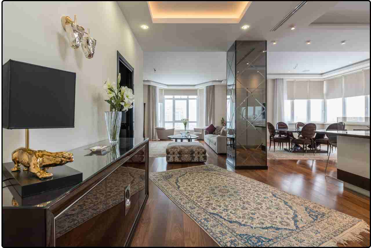 Luxurious living room with a neutral color palette, large flat-screen TV, designer rugs, and high-quality furniture.